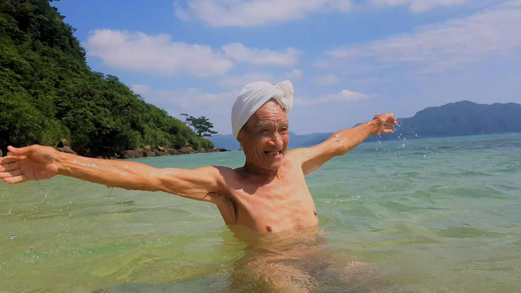 Masafumi Nagasaki in the sea water with his arms open wide 